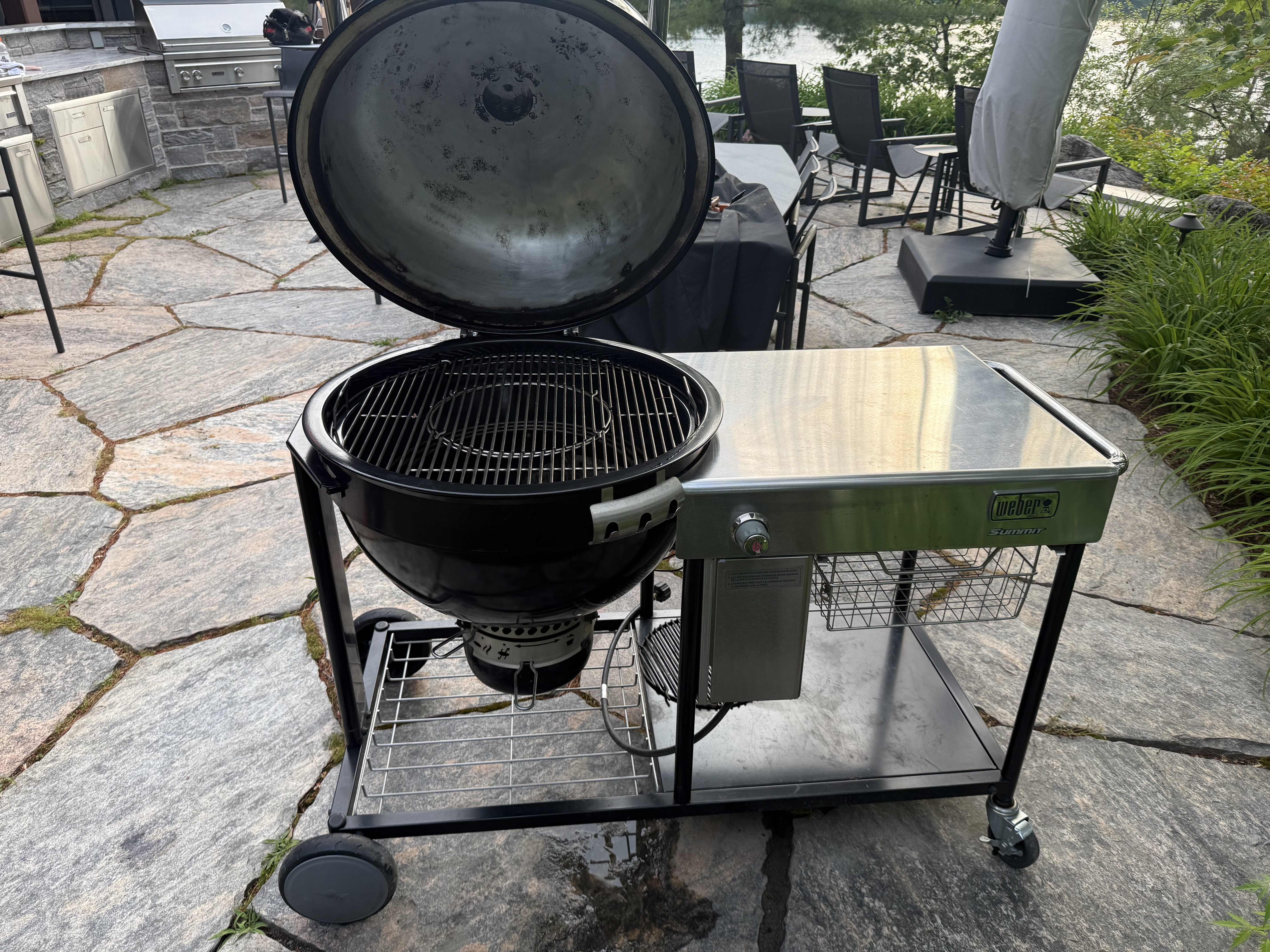 Weber kettle BBQ on a flagstone patio with lake view